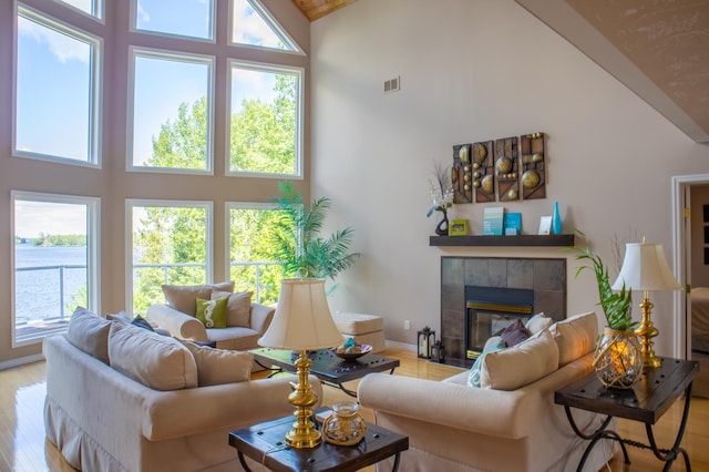 living room featuring light hardwood / wood-style flooring, high vaulted ceiling, and a fireplace