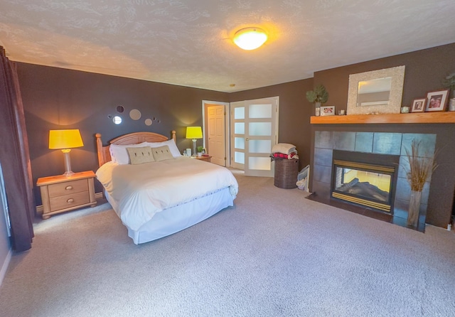 bedroom featuring carpet flooring, a textured ceiling, and a tile fireplace