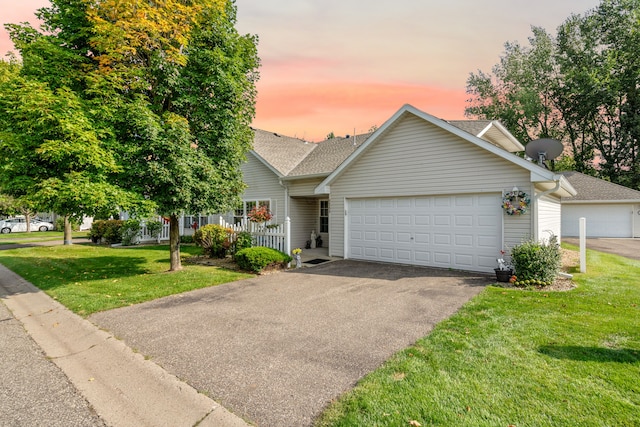 view of front of home with fence, an attached garage, a shingled roof, a front lawn, and aphalt driveway