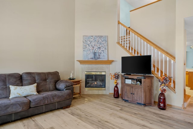 living room with a towering ceiling, light hardwood / wood-style flooring, and a fireplace