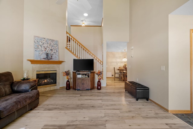 living room featuring a tile fireplace, a high ceiling, and light hardwood / wood-style flooring