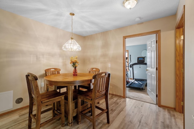 dining room featuring a notable chandelier, light hardwood / wood-style floors, and a textured ceiling