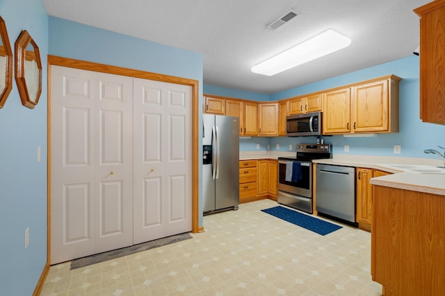 kitchen featuring appliances with stainless steel finishes, a textured ceiling, and sink