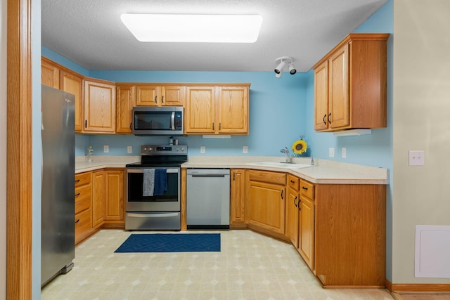 kitchen featuring a textured ceiling, appliances with stainless steel finishes, and sink