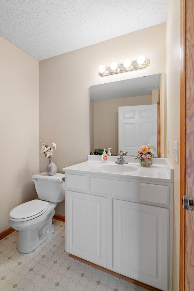 bathroom featuring a textured ceiling, vanity, and toilet