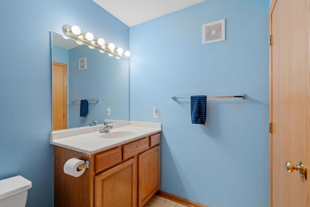 bathroom featuring a textured ceiling, vanity, and toilet