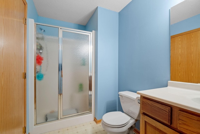 bathroom with a textured ceiling, a shower with door, vanity, and toilet