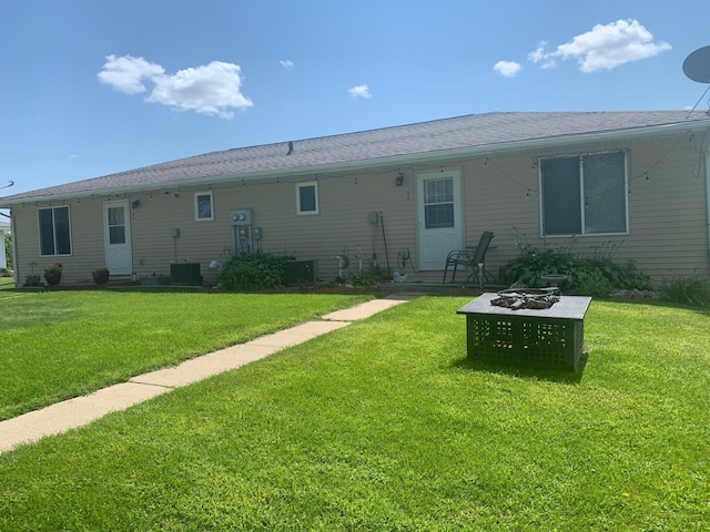 back of house with a fire pit and a lawn