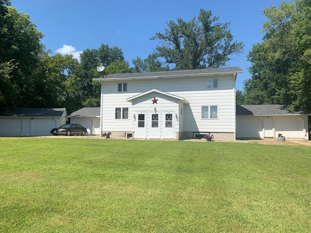 rear view of property featuring a garage, a yard, and an outbuilding