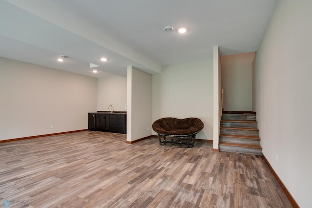 basement with light hardwood / wood-style floors and sink