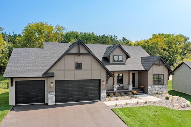 view of front of home with a garage, covered porch, and a front lawn