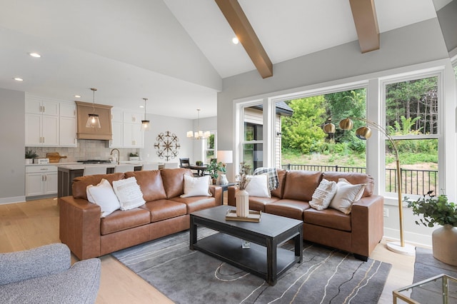 living room featuring sink, a wealth of natural light, an inviting chandelier, and light hardwood / wood-style flooring