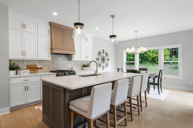 kitchen featuring white cabinetry, sink, and a kitchen island with sink