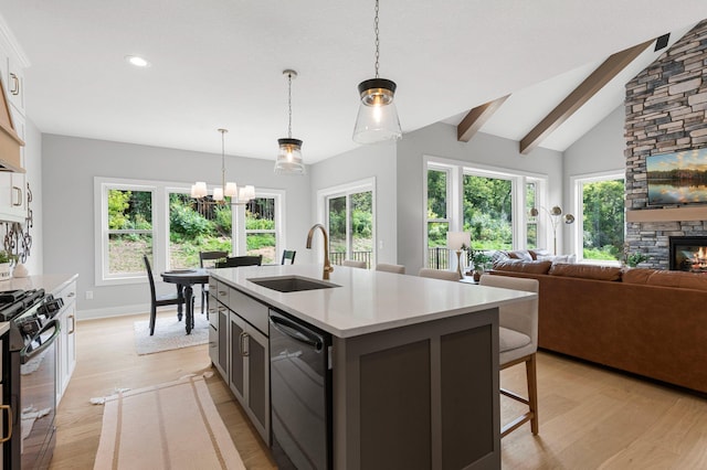 kitchen featuring sink, light hardwood / wood-style flooring, black appliances, white cabinets, and a center island with sink