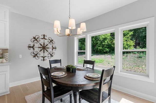 dining space featuring a healthy amount of sunlight, light wood-type flooring, and a notable chandelier