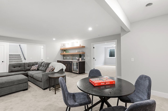 dining space with wine cooler, wet bar, and light carpet