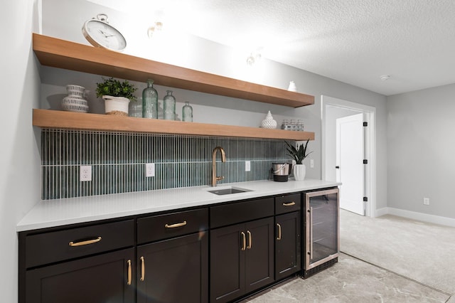 kitchen with wine cooler, sink, light carpet, a textured ceiling, and decorative backsplash