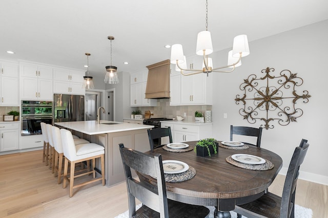 dining room featuring sink, light hardwood / wood-style floors, and a chandelier