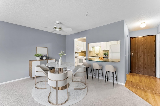 dining room with a textured ceiling, sink, ceiling fan, and light colored carpet