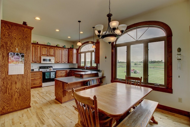 dining space with light wood-style flooring, a chandelier, baseboards, and recessed lighting