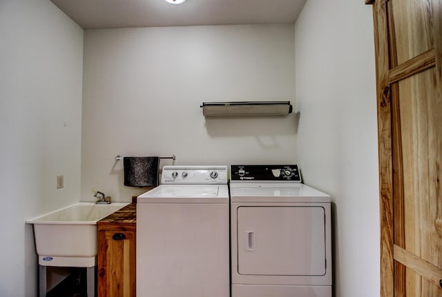 washroom featuring cabinet space, washer and clothes dryer, and a sink