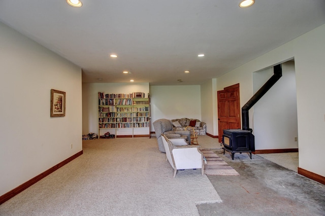 living area featuring recessed lighting, a wood stove, light carpet, and baseboards