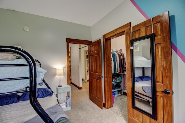 bedroom with light carpet, a closet, a walk in closet, and baseboards