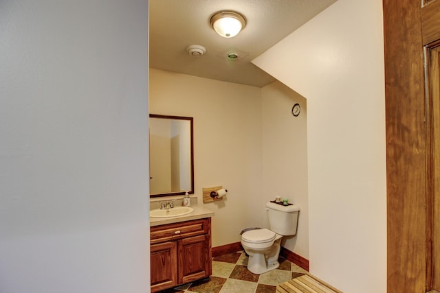 half bath featuring vanity, toilet, and baseboards