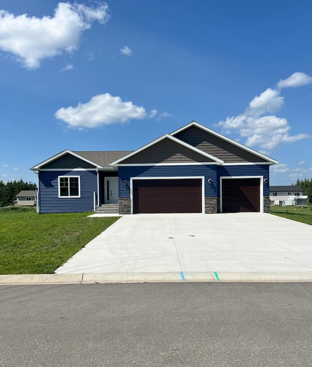 view of front facade with a front yard, a garage, stone siding, and driveway