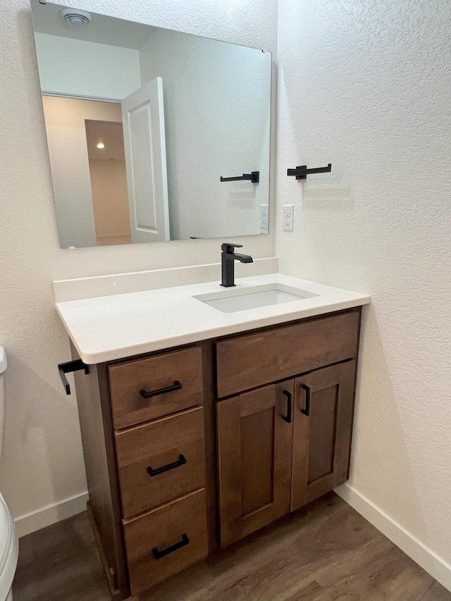 bathroom with vanity, toilet, and hardwood / wood-style floors