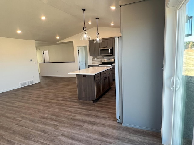 kitchen with a kitchen island, dark wood-type flooring, hanging light fixtures, vaulted ceiling, and appliances with stainless steel finishes