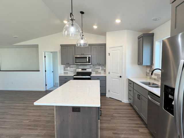 kitchen featuring lofted ceiling, dark wood-type flooring, stainless steel appliances, sink, and a center island