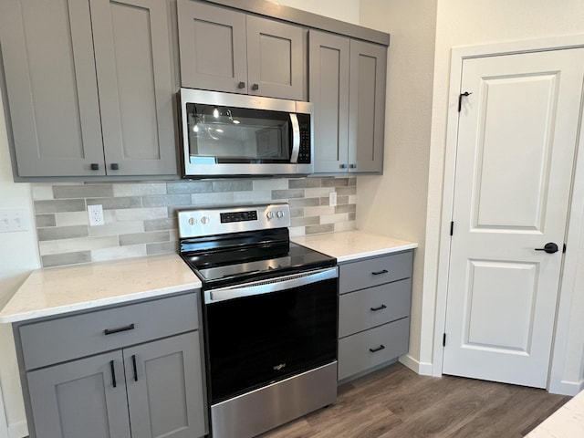 kitchen with dark wood-type flooring, appliances with stainless steel finishes, and gray cabinets