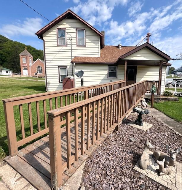 rear view of house with a lawn and a wooden deck