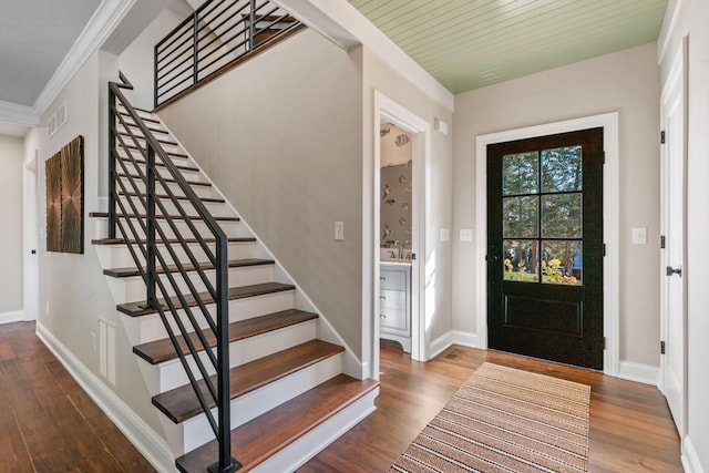 entryway featuring wood-type flooring, ornamental molding, and wood ceiling