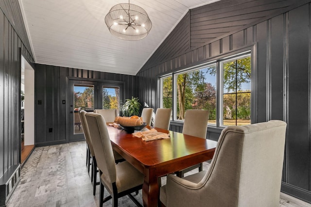 dining space featuring lofted ceiling, wood walls, a chandelier, wooden ceiling, and light hardwood / wood-style flooring