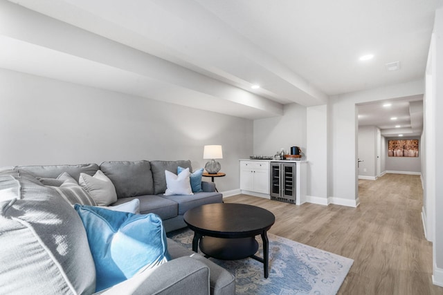 living room featuring light hardwood / wood-style floors, beverage cooler, and bar