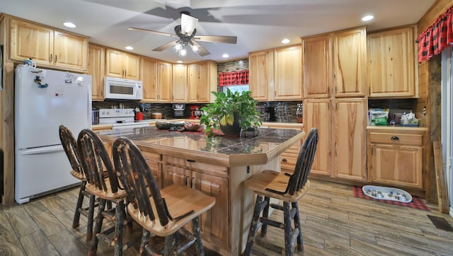 23942 Clover Dr, Merrifield, MN 56465 - kitchen featuring white appliances, a breakfast bar, light brown cabinets, a center island, and wood finished floors