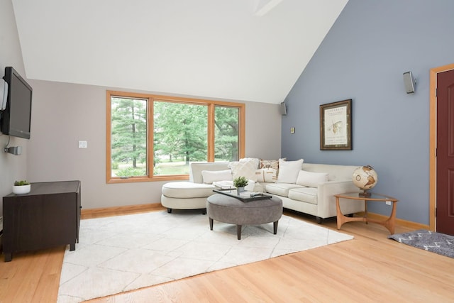 living area with light wood-style flooring, baseboards, and high vaulted ceiling