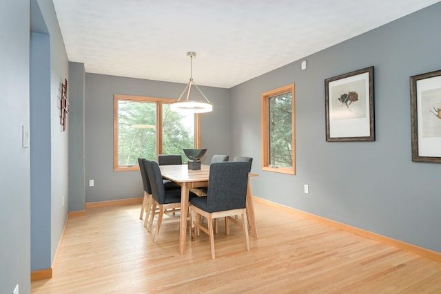 dining space with light wood finished floors and baseboards