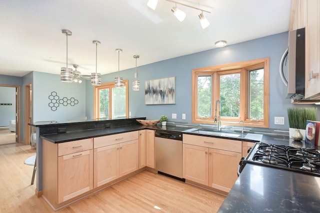 kitchen with light wood-type flooring, light brown cabinetry, a sink, stainless steel appliances, and a peninsula