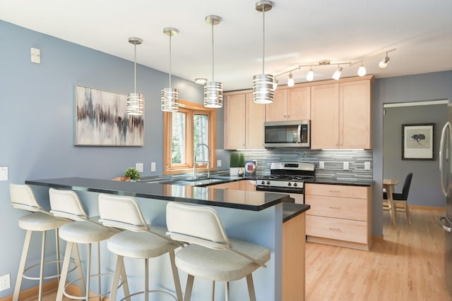 kitchen with light brown cabinetry, a sink, dark countertops, stainless steel appliances, and decorative backsplash