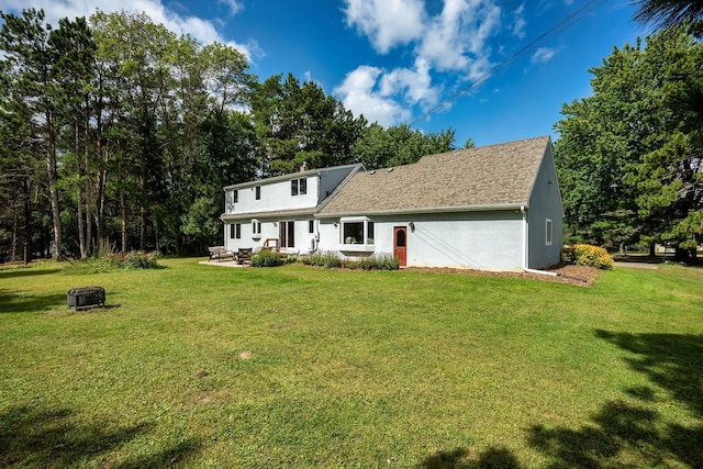 view of front facade with stucco siding, an outdoor fire pit, a front lawn, and roof with shingles