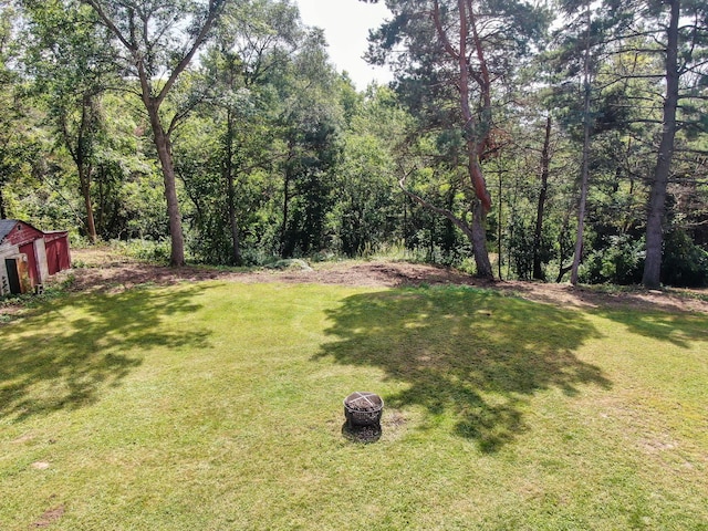 view of yard with a wooded view and a fire pit