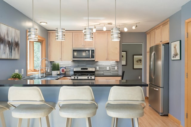 kitchen featuring light brown cabinetry, backsplash, appliances with stainless steel finishes, and a sink