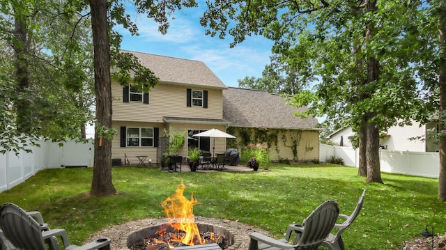 back of property featuring an outdoor fire pit and a yard