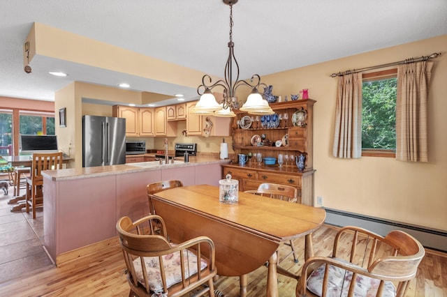 dining room featuring plenty of natural light, a baseboard radiator, a chandelier, and light wood-type flooring