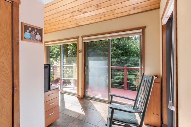 doorway to outside with lofted ceiling, wood ceiling, a healthy amount of sunlight, and dark tile patterned floors