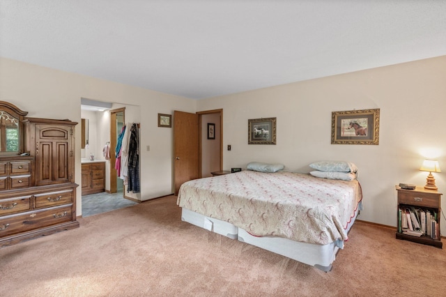 bedroom with light carpet, baseboards, and ensuite bathroom