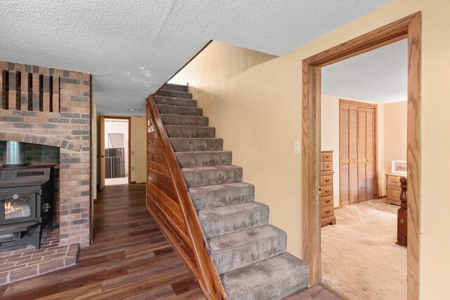 stairs featuring carpet floors, a wood stove, and a textured ceiling